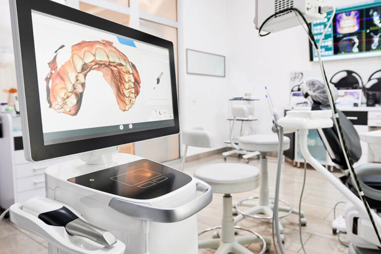 The image shows a modern dental office featuring a digital dental scanner and a computer screen displaying a 3D model of a dental arch.